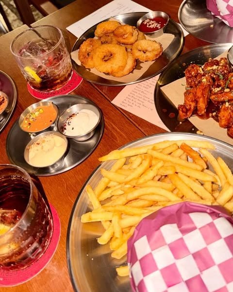Mesa de POYO vista desde arriba con aros de cebolla, tenders, patatas fritas y varias salsas para compartir.