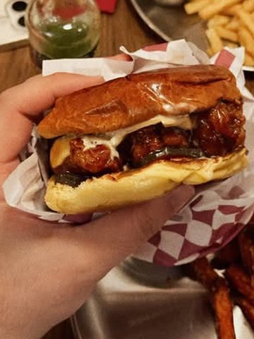 Detalle de un bocadillo de pollo frito de POYO recién montado, envuelto en papel de cuadros.